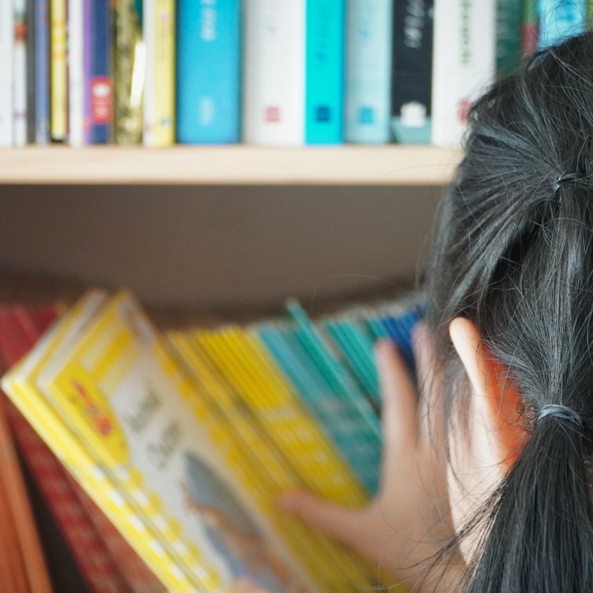 A child choosing a book in the TEC reading corner